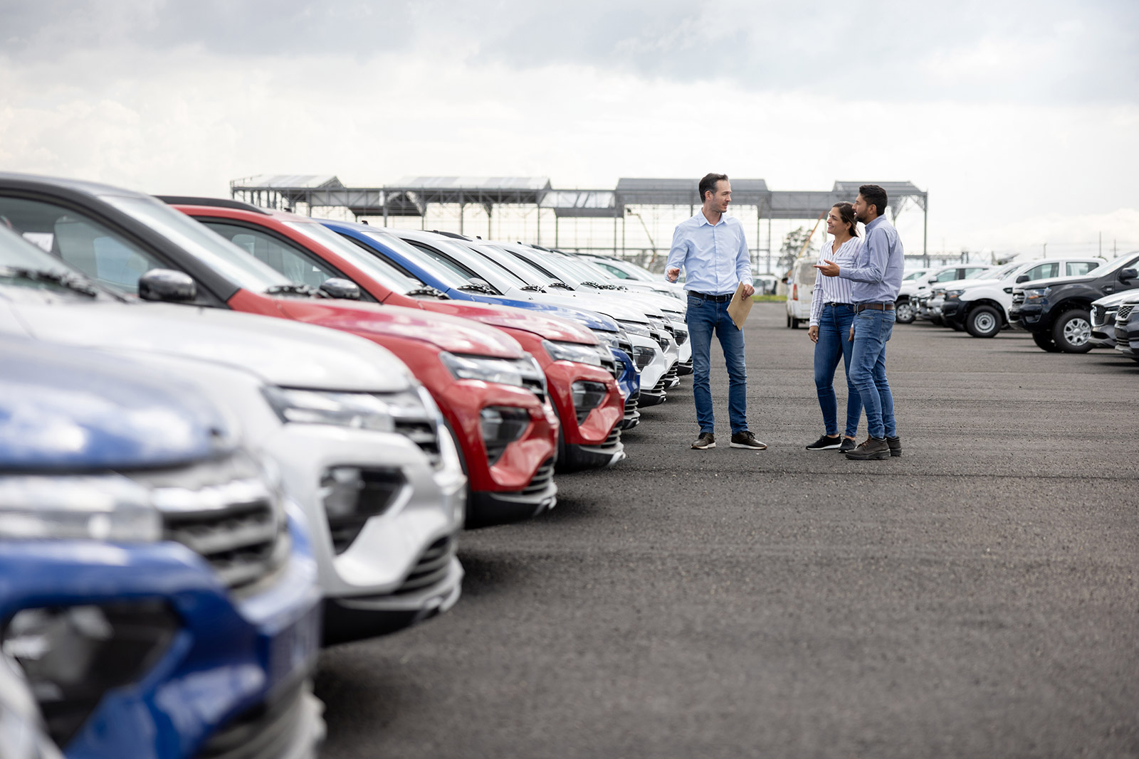 Car Salesman in dealership lot with couple talking