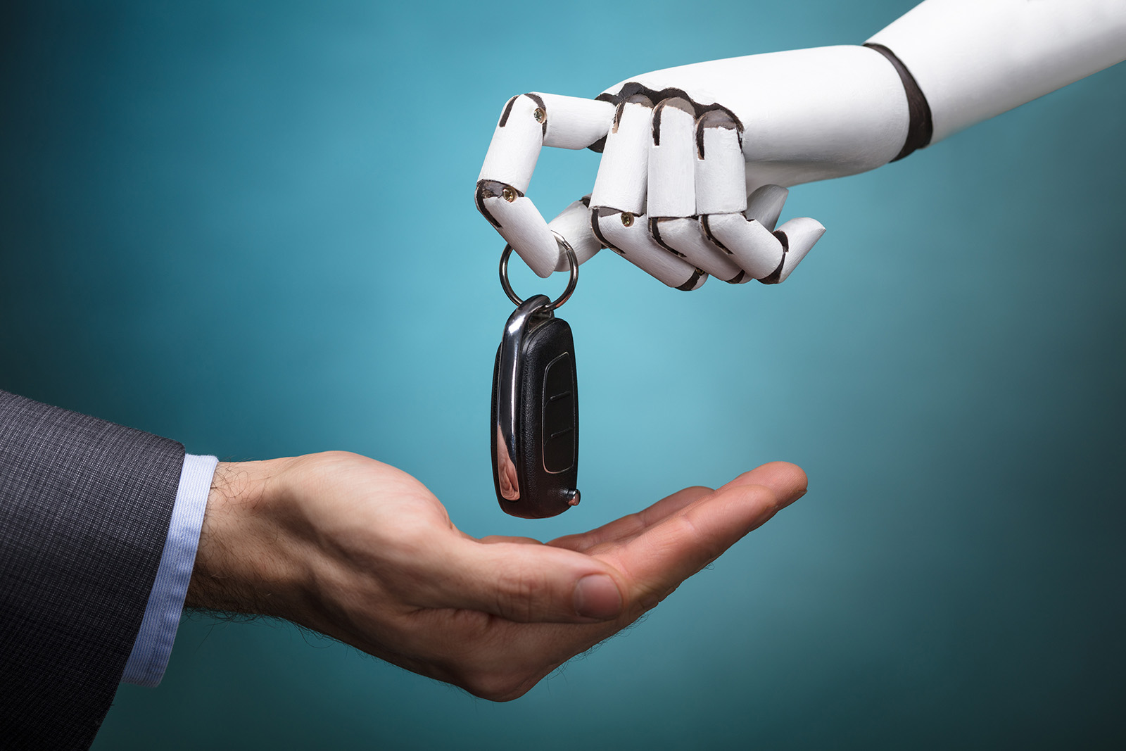 Close-up Of A Robot Giving Car Key To Businessperson On Grey Background